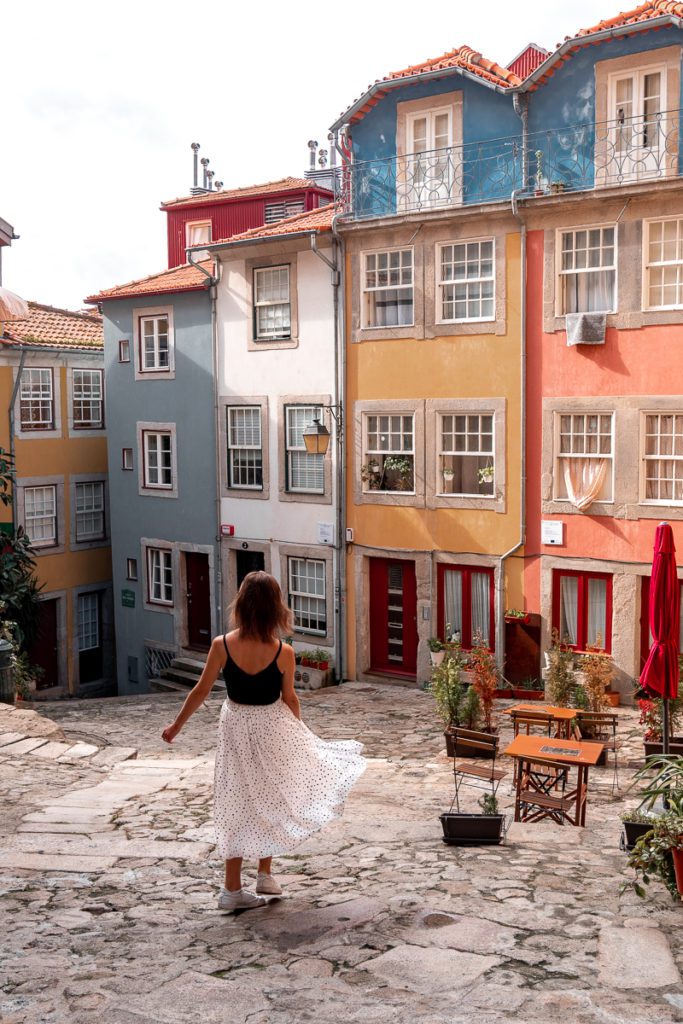 A woman wearing a white skirt walks through Largo da Pena Ventosa